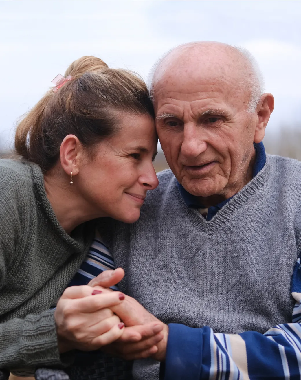 Woman sharing a secret with her elderly father as they hold hands